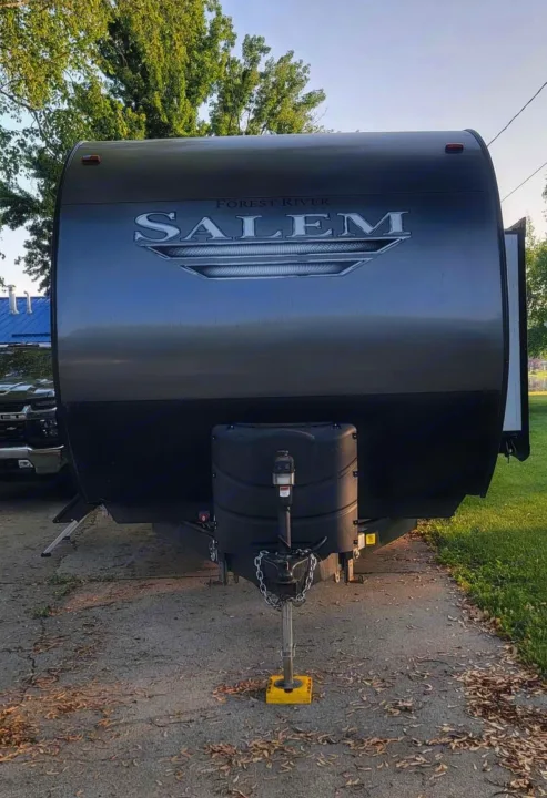 Front view of a dark gray Forest River Salem travel trailer RV rental, parked on asphalt with its hitch down.. Forest River Salem 2019