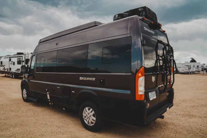 Dark Sequence Class B RV rental camper van parked on a gravel lot under a cloudy sky. Ready for your next trip!. Thor Motor Coach sequence 2021