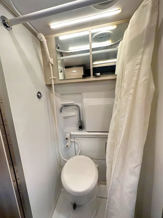 Inside an RV rental: a compact wet bath with a toilet, shower, and small sink, designed for efficient use of space.. Thor Tranquility 2022