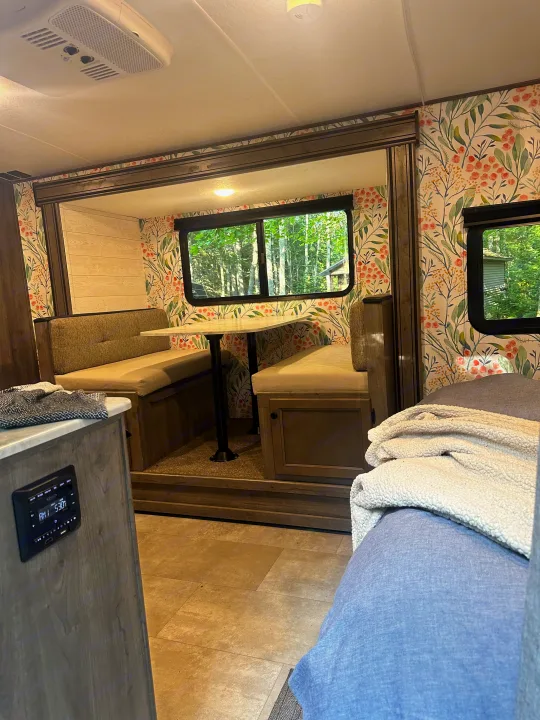 Cozy RV rental interior with a floral dinette, comfy bench seating, and woodland views, perfect for a glamping trip.. Coachmen Apex Nano 2021