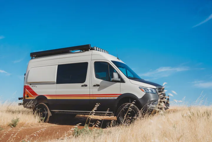 Off-road Storyteller Overland camper van, a great RV rental for adventure. White van with stripes in a golden field.. Storyteller Overland Storyteller Overland Class B 2023