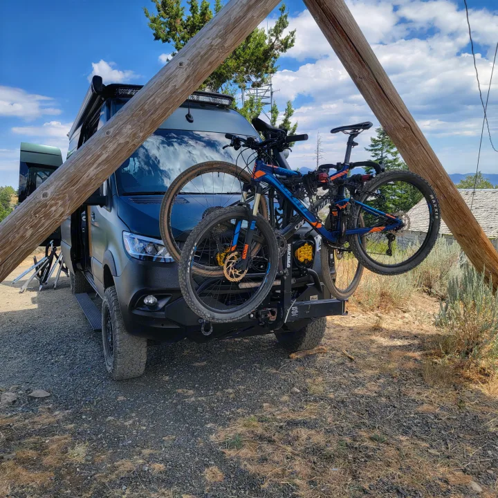 Adventure-ready RV rental van with mountain bikes on a front rack, parked for outdoor travel in a scenic location.. Mercedes-Benz Sprinter 2020
