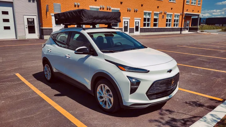 This white electric Chevy Bolt EUV, equipped with a rooftop tent, is ready for an RV rental camping trip.. Chevrolet Other 2023
