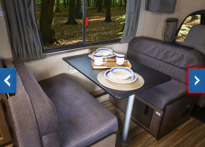RV rental dinette with comfortable seating, a dining table set with dishes, and a scenic forest view through the window.. Thor Majestic 2018