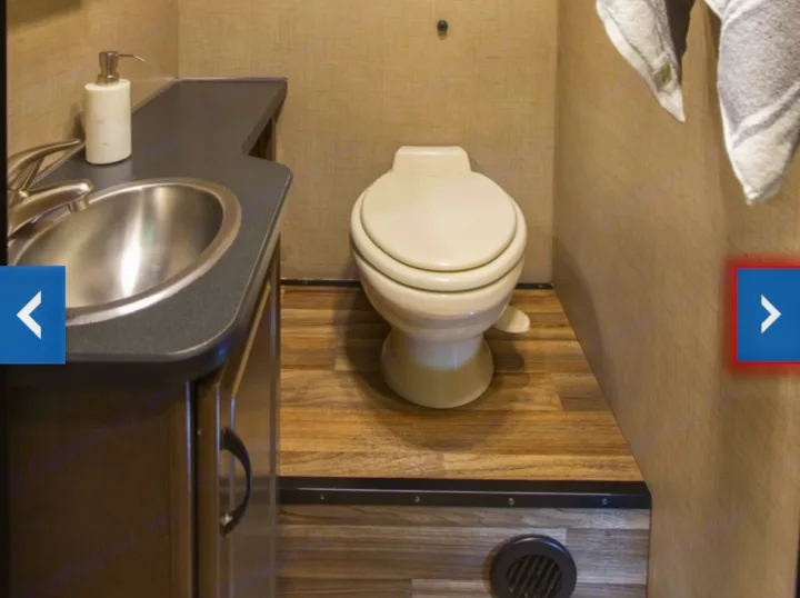 Inside an RV rental bathroom, showing a compact sink, toilet, and wood-look flooring, designed for travel convenience.. Thor Majestic 2018