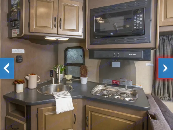Compact RV rental kitchen: sink, two-burner stove, microwave, and wood cabinets for comfortable travel.. Thor Majestic 2018