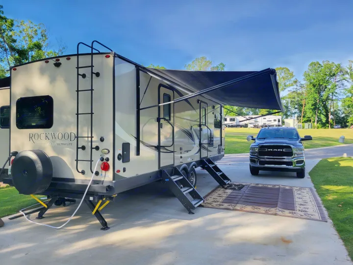 Spacious Rockwood Ultra Lite travel trailer rv rental set up at a sunny campsite with a truck, awning, and outdoor rug.. Forest River Rockwood Ultra Lite 2020