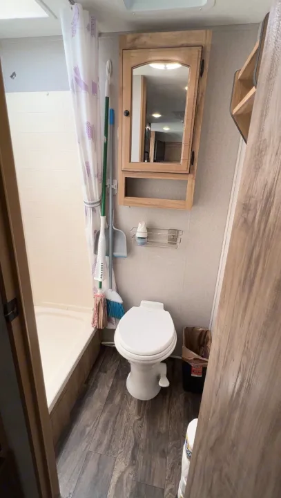 Compact RV rental bathroom: shower, toilet, mirrored cabinet, and wood-look floor. Organized travel space.. Coachmen Other 2019