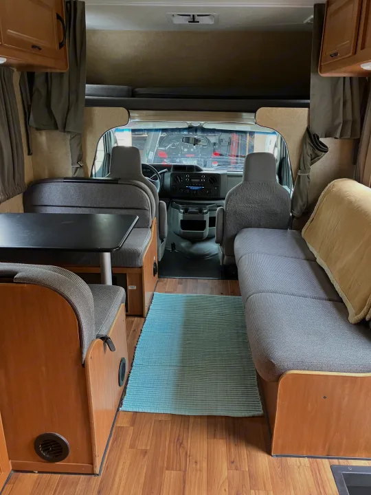 An RV rental's inviting interior, showing the dining area, sofa seating, and the front cockpit from the living space.. Majestic Ford 2018
