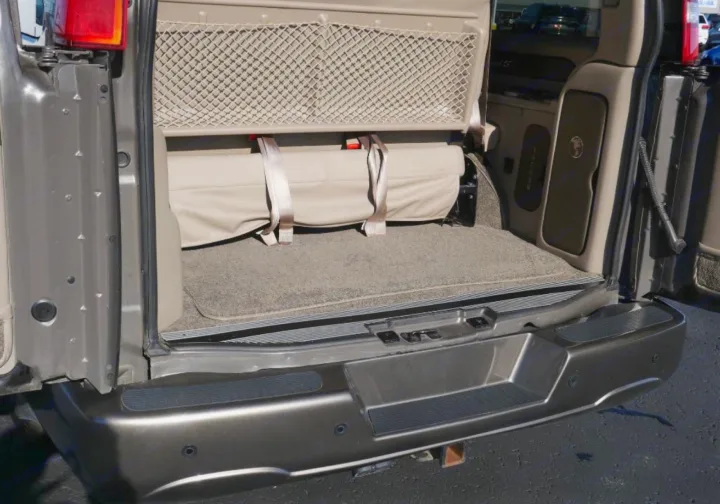 Rear of an RV rental showing organized cargo area: carpeted floor, secured beige bedding, and storage net. Ready for adventure.. Chevrolet 2500 2019