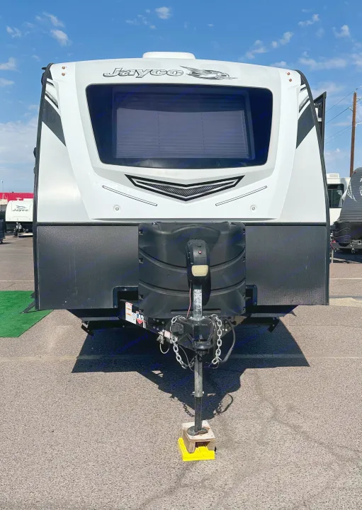 White Jayco RV rental, front view showcasing the travel trailer's hitch & tanks, under a bright sky.. Jayco White Hawk 2020