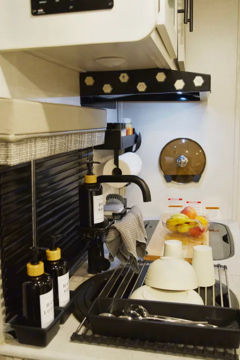 Experience comfort in this RV rental's well-equipped kitchen, featuring a sink, drying rack with dishes, soaps, and fresh fruit.. Forest River R-Pod 193 2022