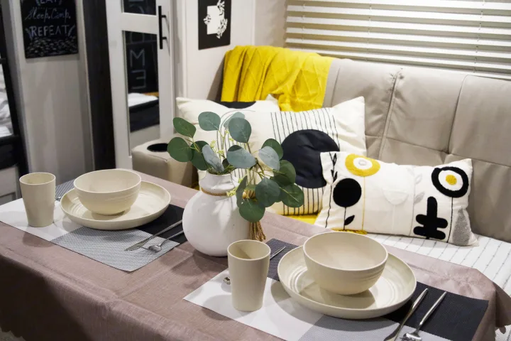 Cozy RV rental interior with a modern dining area set for two, featuring stylish decor and comfortable sofa seating.. Forest River R-Pod 193 2022