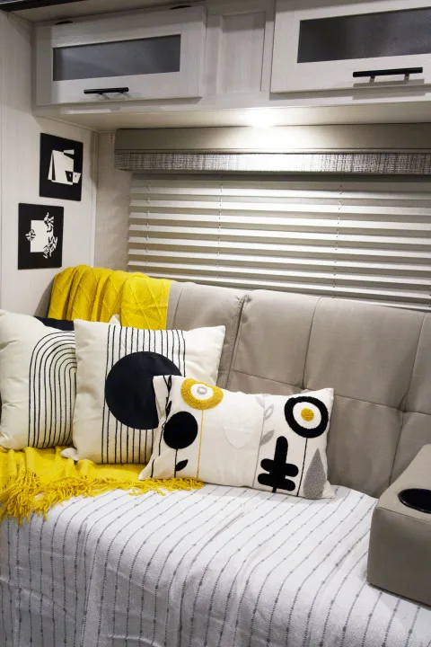 Cozy RV rental interior with a gray couch, bright yellow throw, modern abstract pillows, and overhead cabinets.. Forest River R-Pod 193 2022