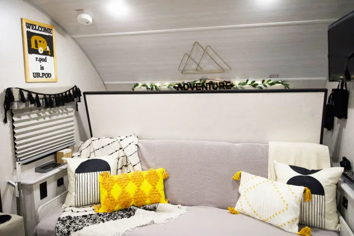 Cozy RV rental interior: a comfy bed adorned with colorful pillows, adventure decor, and practical amenities.. Forest River R-Pod 193 2022