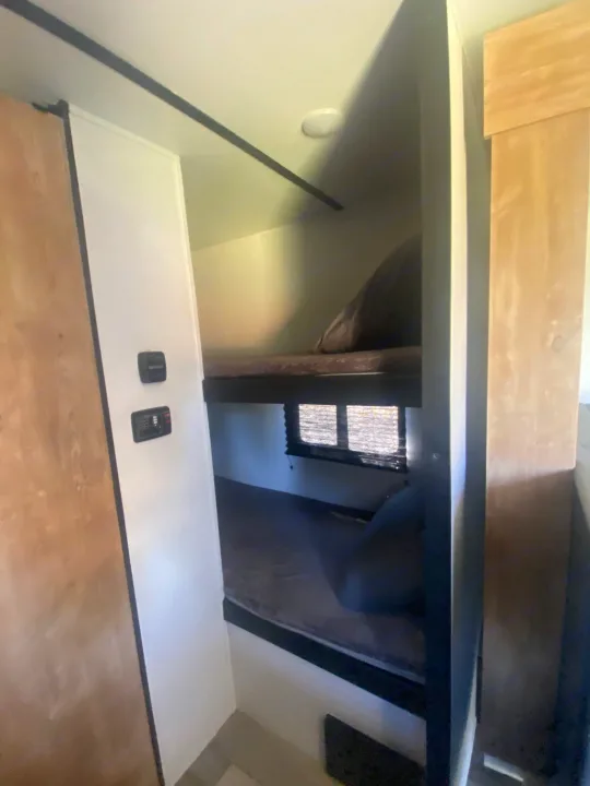 Inside this RV rental, dual bunk beds and control panels create a compact, functional sleeping space.. Keystone RV Springdale 2022