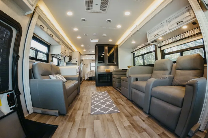 Spacious RV rental interior: modern living space with comfortable seating, full kitchen, and hallway leading to bedroom.. Entegra Coach Vision XL 2021