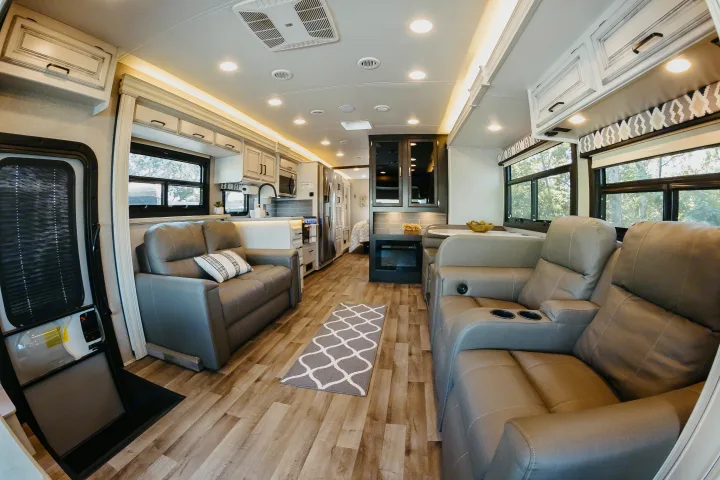 Step inside this inviting RV rental: a modern living space with plush seating, full kitchen, and dining area on wood-look floors.. Entegra Coach Vision XL 2021