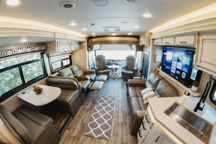 Explore this spacious RV rental interior, featuring a living room, dining booth, kitchen, and TV area. Ideal for road trips.. Entegra Coach Vision XL 2021
