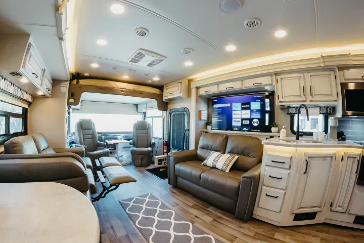 Bright, spacious RV rental interior with comfortable living area, TV, functional kitchen, and overhead bed. Ready for adventures!. Entegra Coach Vision XL 2021
