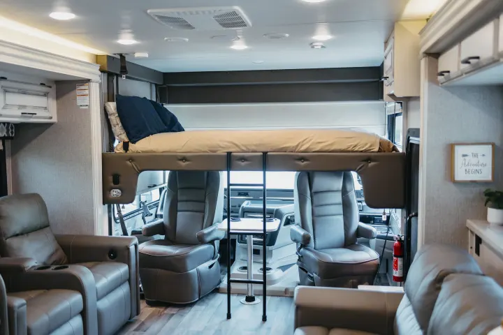 Spacious RV rental interior featuring an overhead bunk bed, swiveling front seats, and comfortable living area recliners.. Entegra Coach Vision XL 2021