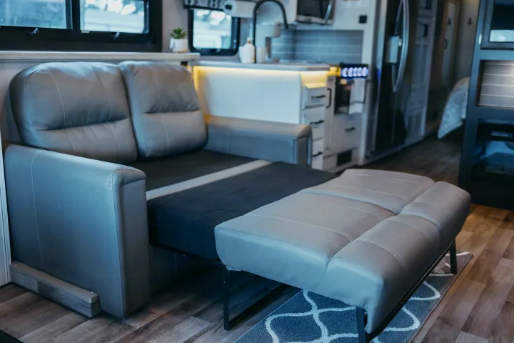 A grey pull-out sofa bed in an RV rental, offering versatile sleeping in a modern living space.. Entegra Coach Vision XL 2021