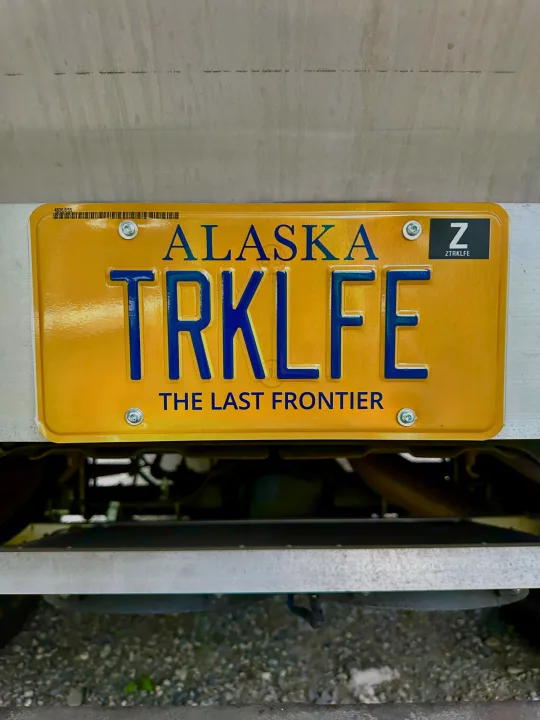 Alaska's custom 'TRKLFE' license plate on an RV rental vehicle, showcasing 'The Last Frontier'.. Ford F250 1997