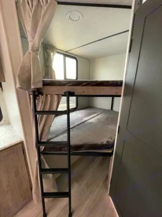 Comfortable bunk beds in an RV rental interior. Ideal for families, featuring a ladder and cozy sleeping areas.. Forest River Surveyor Legend 2024