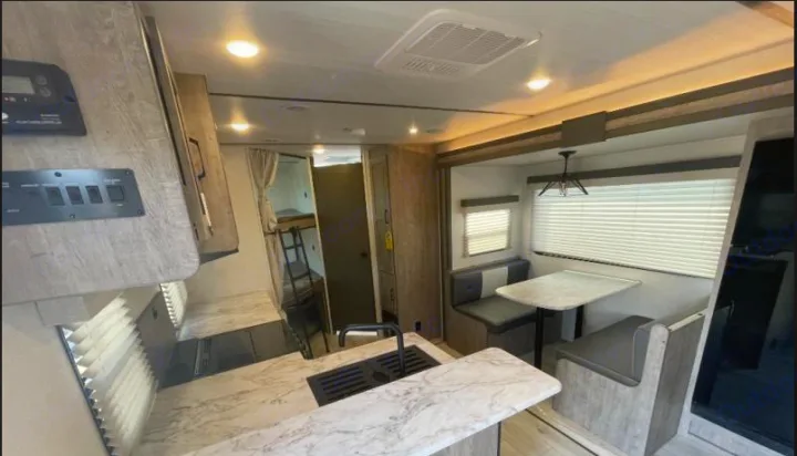 Modern RV rental interior features a functional kitchen, dining booth, and cozy bunk beds. Perfect for family adventures.. Forest River Surveyor Legend 2024
