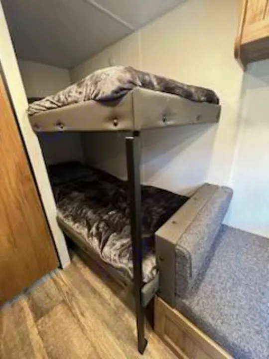 Cozy RV rental bunk beds. This sleeping area features two stacked beds with plush gray blankets, perfect for family adventures.. Forest River Cherokee 2024