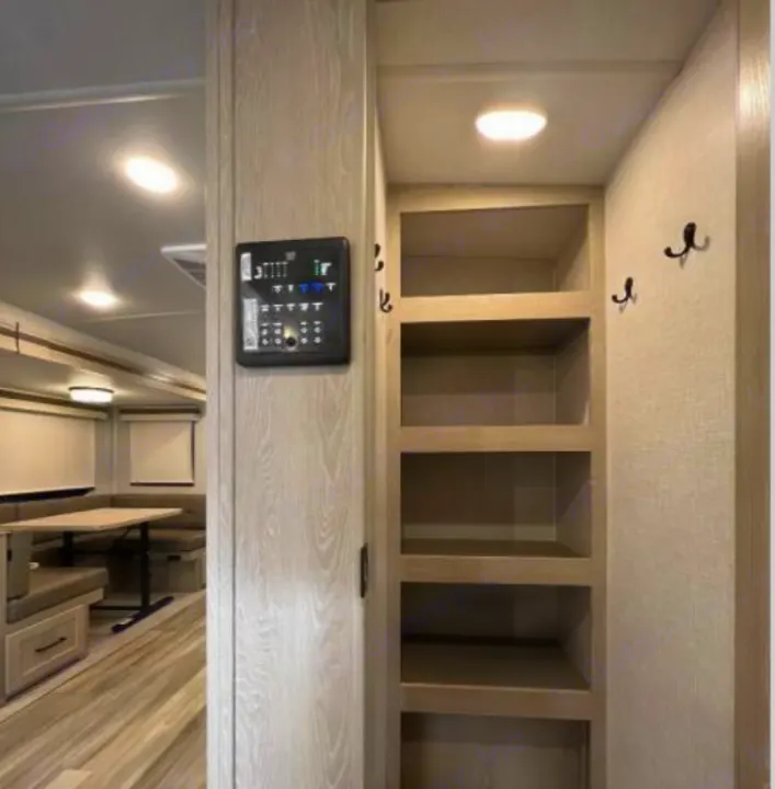 This RV rental's interior features a central control panel, built-in shelving for storage, and a cozy dinette.. Forest River Rockwood Ultra Lite 2023