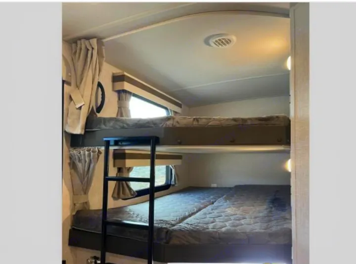Spacious RV rental bunk beds with comfortable mattresses, ideal for family trips. Features ladder & windows.. Forest River Rockwood Ultra Lite 2023