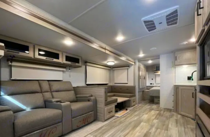 Luxury RV rental interior: spacious living area with recliners, dining booth, full kitchen, and bedroom access.. Forest River Rockwood Ultra Lite 2023