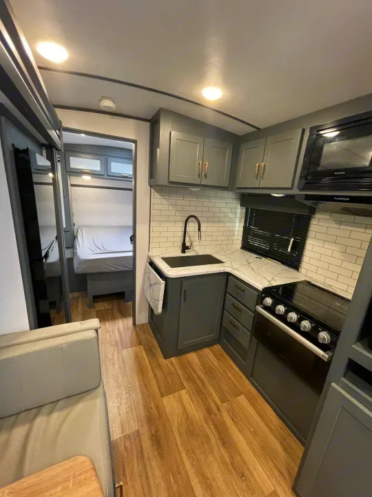 Modern RV rental interior featuring a full kitchen, cozy living area, and a glimpse of the bedroom.. Keystone RV Bullet Ultra Lite 2023