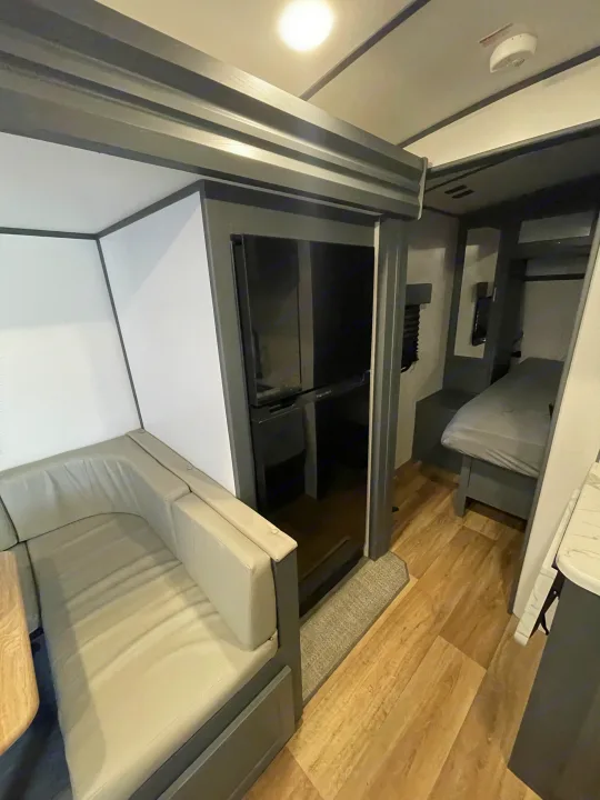 Inside this RV rental: L-shaped sofa dinette, refrigerator, and bedroom, showcasing the functional and comfortable layout.. Keystone RV Bullet Ultra Lite 2023