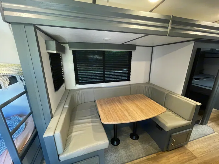 This RV rental offers a compact dinette with table & bench seating, plus nearby bunk beds for comfortable travel.. Keystone RV Bullet Ultra Lite 2023