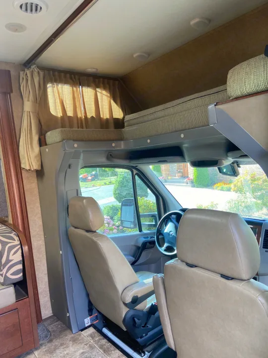 Spacious RV rental interior with over-cab bunk & front seats, ideal for travel.. Solera Solera Motorhome 2014