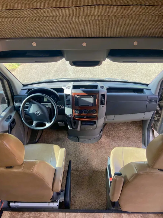 Inside this RV rental: a clean cockpit with a Mercedes-Benz steering wheel, dashboard, and comfortable front seats.. Solera Solera Motorhome 2014