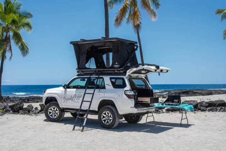RV rental: White Toyota 4Runner with rooftop tent and full camp kitchen set up on a scenic Hawaiian beach.. Custom Toyota 4Runner TRD Off-Road 2023