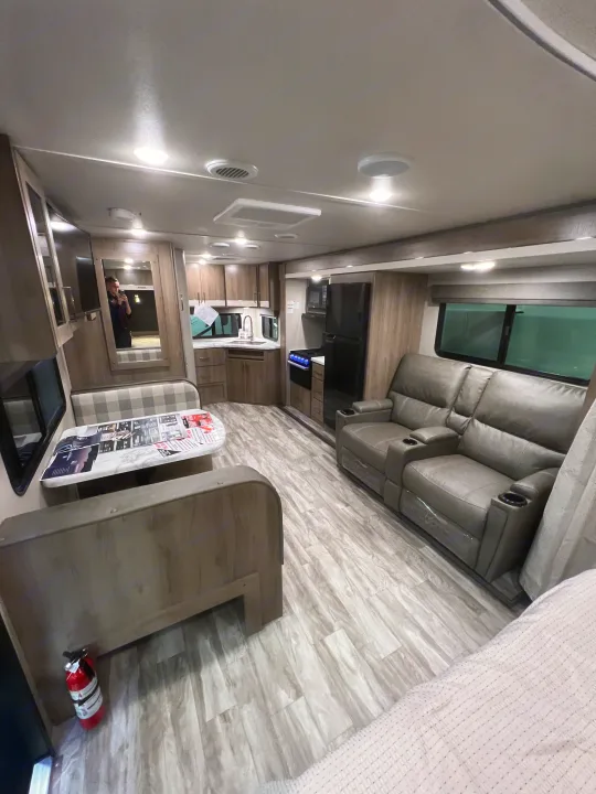 Explore this comfortable rv rental interior: gray recliners, dinette, and a well-equipped kitchen await your next adventure.. Grand Design Imagine 2023
