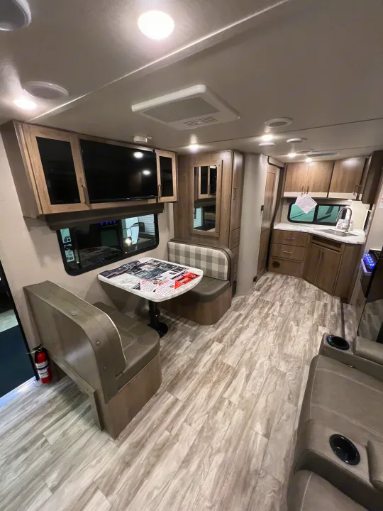 RV rental interior: modern dinette, full kitchen, light wood-look floor, & cozy recliners.. Grand Design Imagine 2023