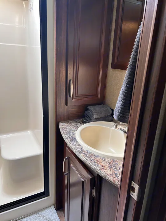 Compact RV rental bathroom featuring a shower, vanity, and sink, designed for efficiency.. Keystone RV Montana Mountaineer 2015