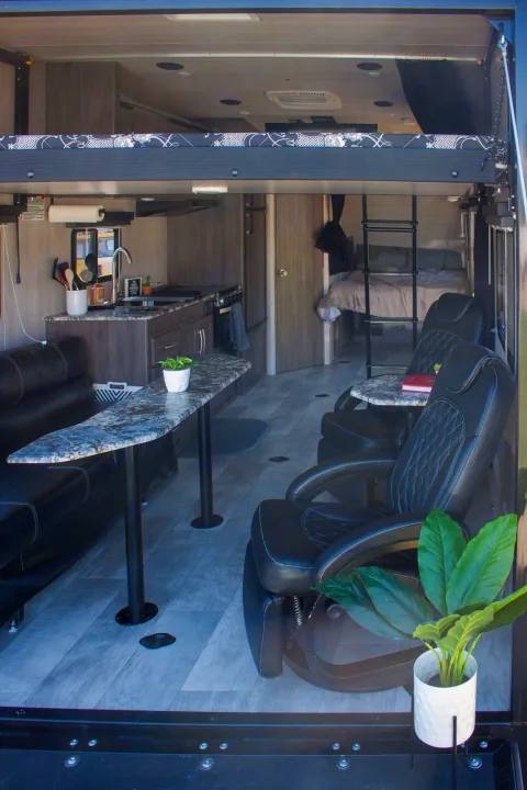 Inside an RV rental: full kitchen, comfy recliners, dining table, and multiple sleeping areas, including a bunk and private bed.. Genesis Supreme Rv Genesis Supreme 2022