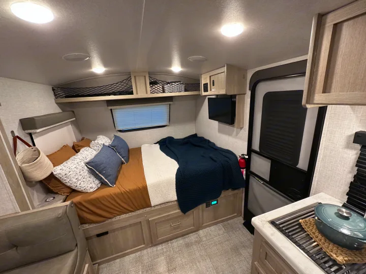 Explore this inviting RV rental interior, showcasing a cozy bed, compact kitchen, and lounge space.. Forest River Rockwood Geo Pro 2021