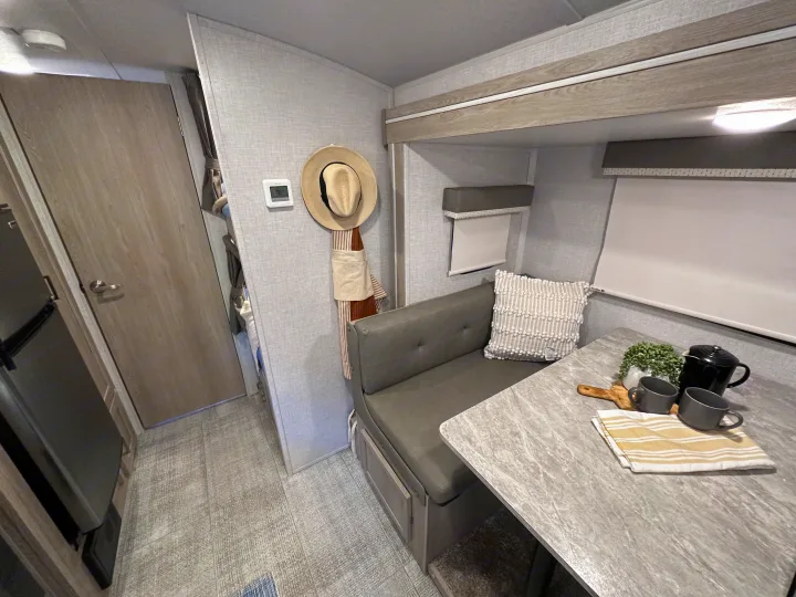 Cozy RV rental interior showcasing a gray dinette area with a modern table set for coffee, along with compact storage and controls.. Forest River Rockwood Geo Pro 2021