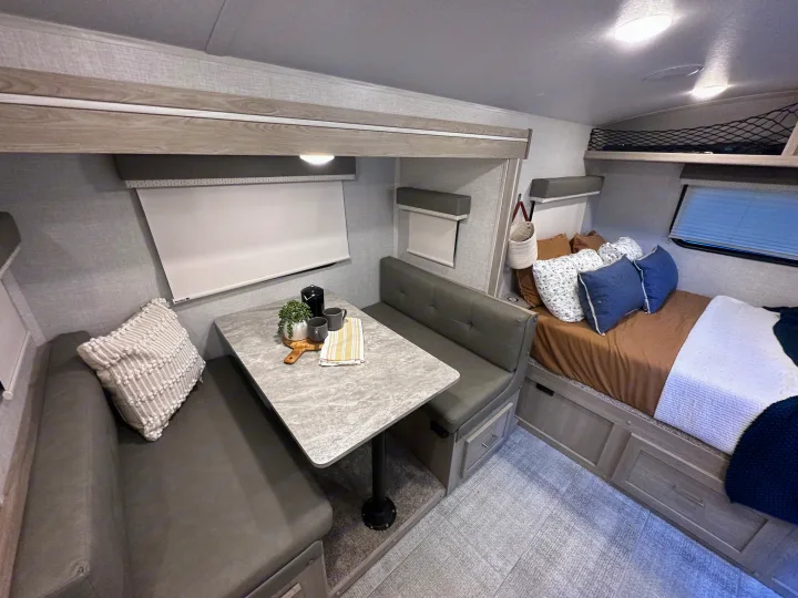 Inside a sleek RV rental: a modern dinette, cozy bed with pillows, and smart storage solutions for comfortable travel.. Forest River Rockwood Geo Pro 2021