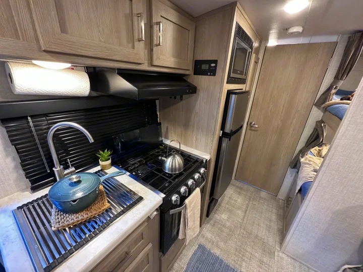 RV rental interior: full kitchen with sink, stove, microwave, fridge, plus bunk beds. Ready for your adventure!. Forest River Rockwood Geo Pro 2021