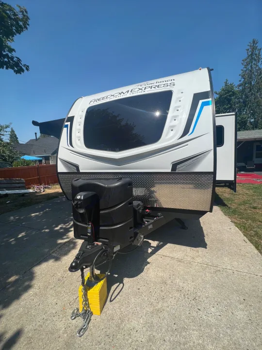 A white Coachmen Freedom Express RV, ideal for an rv rental, parked on a sunny day under a blue sky.. Coachmen 257BHS 2022