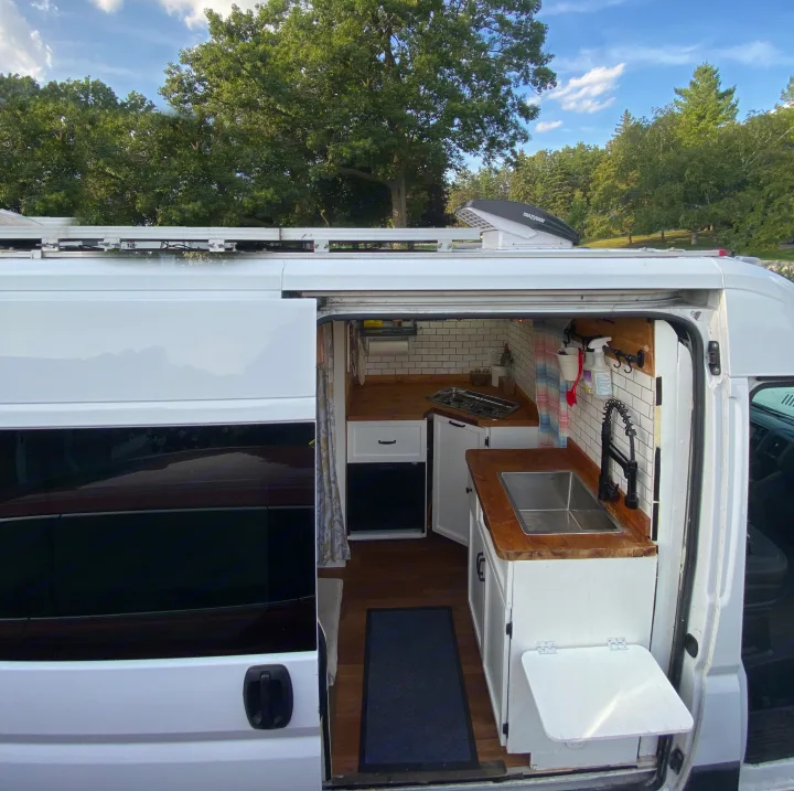 RV rental: A bright white camper van's open side door reveals a modern, compact mobile kitchen with wood counters and a sink.. Other Other 2015