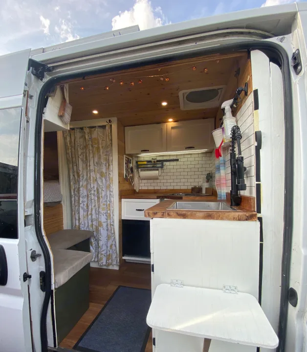 Cozy rv rental interior: functional kitchen, wood accents, and comfortable seating in a compact camper van.. Other Other 2015